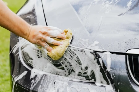 Hand washing a car with a sponge